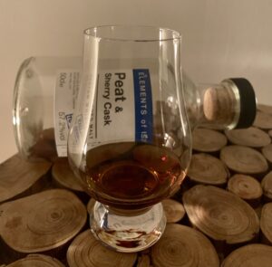 Ein Glas mit Peat & Sherry Blended Islay Malt vor einer liegenden Flasche
